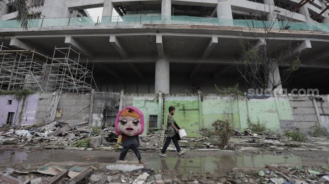 Pengamen berjalan melintasi di Kampung Bayam, Papanggo, Tanjung Priok, Jakarta Utara, Sabtu (3/4/2021). [Suara.com/Angga Budhiyanto]