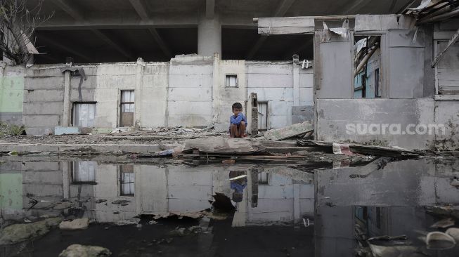 Seorang anak bermain di Kampung Bayam, Papanggo, Tanjung Priok, Jakarta Utara, Sabtu (3/4/2021). [Suara.com/Angga Budhiyanto]