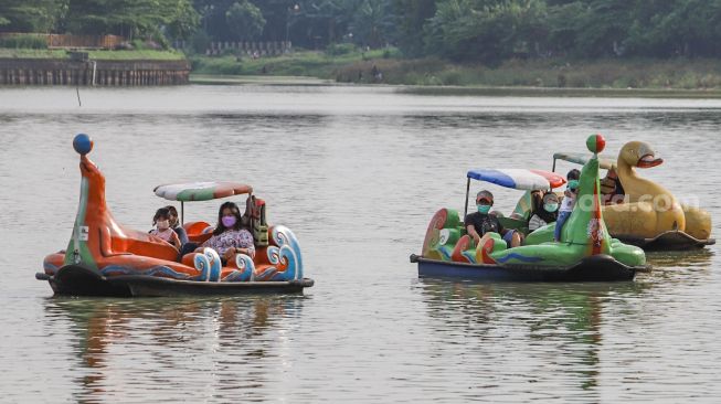 Warga menaiki wahana air saat berwisata di Perkampungan Budaya Betawi Setu Babakan, Jakarta Selatan, Minggu (4/4/2021). [Suara.com/Alfian Winanto]