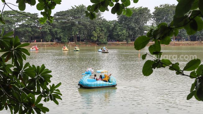 Warga menaiki wahana air saat berwisata di Perkampungan Budaya Betawi Setu Babakan, Jakarta Selatan, Minggu (4/4/2021). [Suara.com/Alfian Winanto]