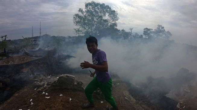 Warga menghindari asap usai mencoba memadamkan api yang membakar areal sekitar kuburan Cina saat pelaksanaan tradisi ceng beng (ziarah kubur) di Jambi, Minggu (4/4/2021). ANTARA FOTO/Wahdi Septiawan
