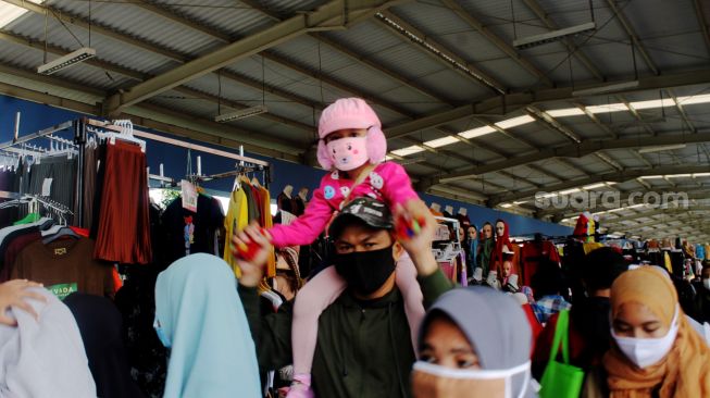 Seorang anak kecil yang digendong oleh orang tuanya saat berada di Skybridge Pasar Tanah Abang, Jakarta, Minggu (04/04/21). [Suara.com/Dian Latifah]
