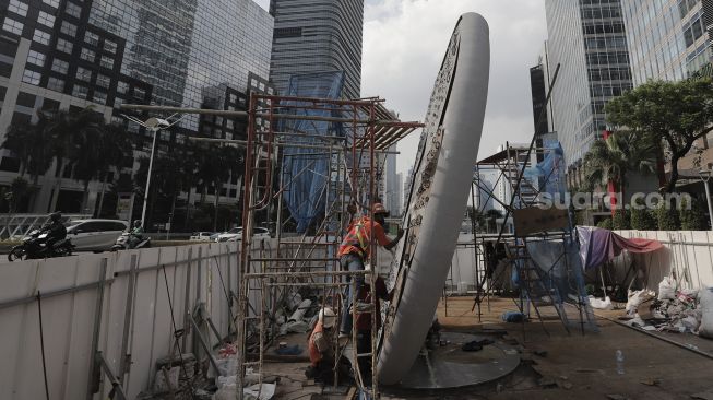 Pekerja menyelesaikan pembangunan Tugu Sepeda di Jalan Jenderal Sudirman, Jakarta, Senin (5/4/2021). [Suara.com/Angga Budhiyanto]