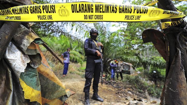 Polisi berjaga di sumur minyak yang dipasangi garis polisi saat operasi penertiban di Taman Hutan Raya Sultan Thaha Syaifuddin, Batanghari, Jambi, Senin (5/4/2021). [ANTARA FOTO/Wahdi Septiawan]