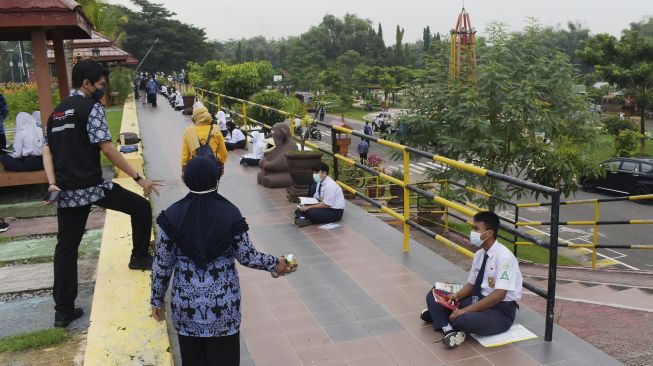 Murid Sekolah Menengah Pertama (SMP) mengikuti pembelajaran di luar kelas di Taman Bantaran Sungai Madiun, Kota Madiun, Jawa Timur, Selasa (6/4/2021). [ANTARA FOTO/Siswowidodo]