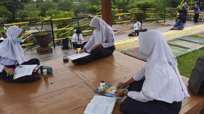 Murid Sekolah Menengah Pertama (SMP) mengikuti pembelajaran di luar kelas di Taman Bantaran Sungai Madiun, Kota Madiun, Jawa Timur, Selasa (6/4/2021). [ANTARA FOTO/Siswowidodo]