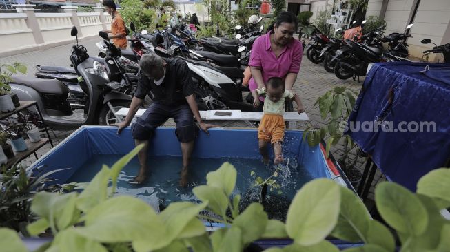 Warga melakukan terapi menggunakan ikan (fish spa) di ruang edukasi anak di halaman Kantor Kelurahan Karet, Jakarta, Rabu (7/4/2021). [Suara.com/Angga Budhiyanto]