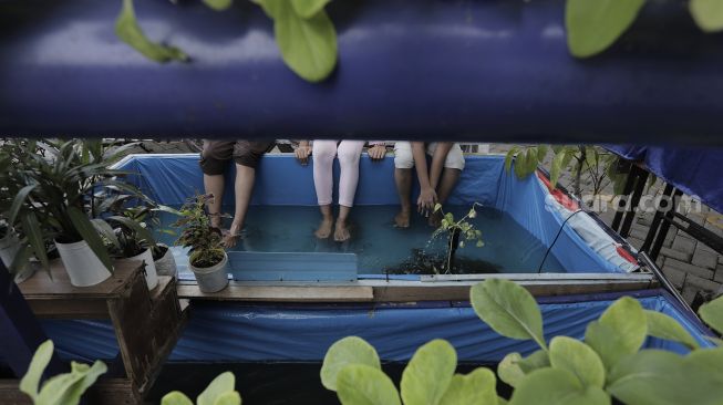 Warga melakukan terapi menggunakan ikan (fish spa) di ruang edukasi anak di halaman Kantor Kelurahan Karet, Jakarta, Rabu (7/4/2021). [Suara.com/Angga Budhiyanto]