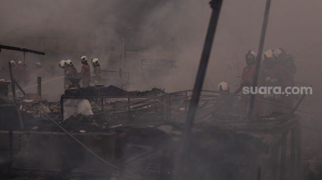 Petugas pemadam kebakaran berusaha memadamkan api yang membakar Pasar Lontar atau Pasar Kambing di Jalan Sabeni, Tanah Abang, Jakarta, Kamis (8/4/2021). [Suara.com/Angga Budhiyanto]