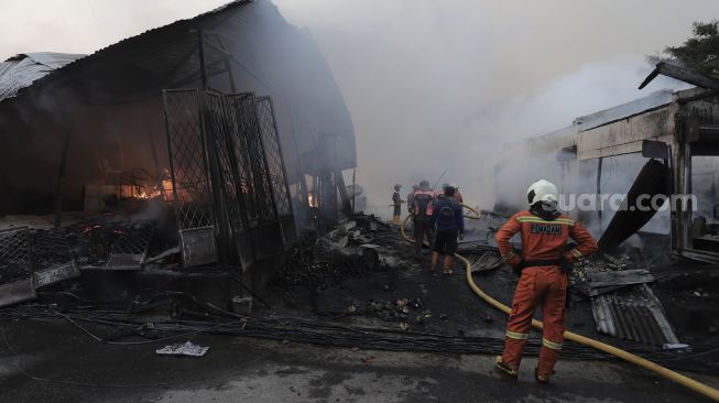 Petugas pemadam kebakaran berusaha memadamkan api yang membakar Pasar Lontar atau Pasar Kambing di Jalan Sabeni, Tanah Abang, Jakarta, Kamis (8/4/2021). [Suara.com/Angga Budhiyanto]