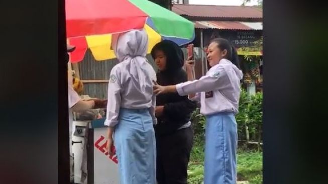 Bikin Ngakak, Wanita SMA Ini Pakai Helm Berlapis Hijab saat Jajan Leker