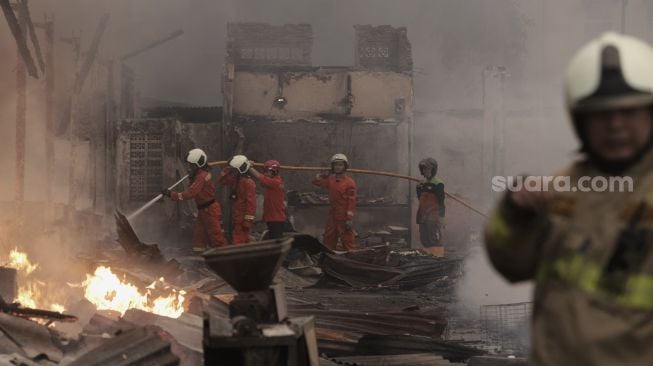 Petugas pemadam kebakaran berusaha memadamkan api yang membakar Pasar Lontar atau Pasar Kambing di Jalan Sabeni, Tanah Abang, Jakarta, Kamis (8/4/2021). [Suara.com/Angga Budhiyanto]