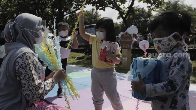 Sejumlah siswa taman kanak-kanak (TK) menunjukkan miniatur beduk buatannya saat mengikuti proses pembelajaran secara Drive in Learning (DRIL) di area parkir Padepokan Pencak Silat Indonesia, Jakarta, Kamis (8/4/2021). [Suara.com/Angga Budhiyanto]