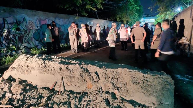 Petugas gabungan Satpol PP bersama TNI-Polri membongkar dinding pemblokir akses jalan menuju sebuah pergudangan di Cipondoh, Kota Tangerang, Rabu (7/4/2021) malam. [Dok. Satpol PP Kota Tangerang]