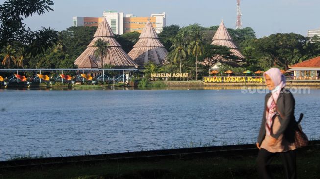 Pengunjung berjalan melewati anjungan air tawar di TMII, Jakarta Timur, Kamis (08/4/21). [Suara.com/Dian Latifah