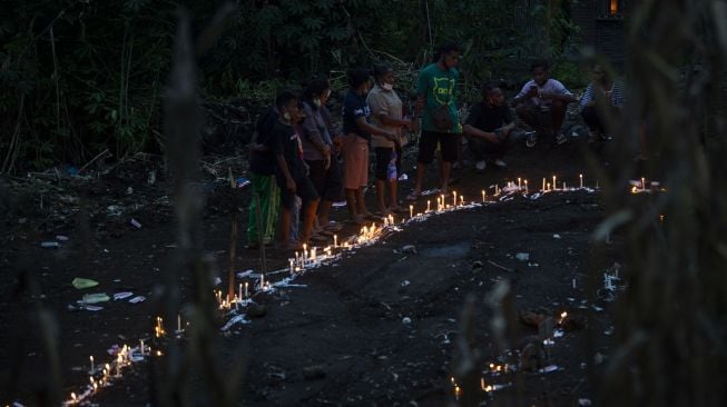 Sejumlah warga menyalakan lilin saat berziarah di tempat pemakaman massal korban tanah longsor di Desa Nelelamadike, Kecamatan Ile Boleng, Kabupaten Flores Timur, Nusa Tenggara Timur (NTT), Rabu (7/4/2021).  ANTARA FOTO/Aditya Pradana Putra