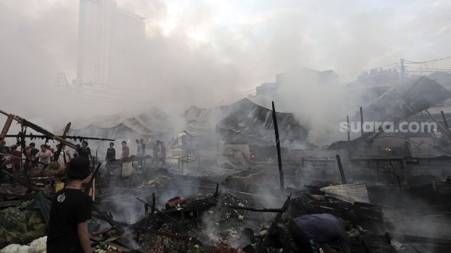 Warga menyaksikan kebakaran yang melanda Pasar Lontar atau Pasar Kambing di Jalan Sabeni, Tanah Abang, Jakarta, Kamis (8/4/2021). [Suara.com/Angga Budhiyanto]