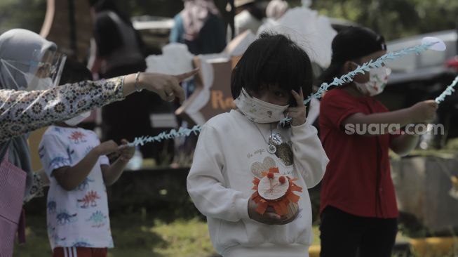 Siswa taman kanak-kanak (TK) menunjukkan miniatur beduk buatannya saat mengikuti proses pembelajaran secara Drive in Learning (DRIL) di area parkir Padepokan Pencak Silat Indonesia, Jakarta, Kamis (8/4/2021). [Suara.com/Angga Budhiyanto]