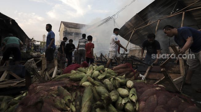 Warga menyelamatkan barang dagangannya dari kebakaran yang melanda Pasar Lontar atau Pasar Kambing di Jalan Sabeni, Tanah Abang, Jakarta, Kamis (8/4/2021). [Suara.com/Angga Budhiyanto]