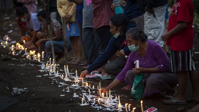 Sejumlah warga menyalakan lilin saat berziarah di tempat pemakaman massal korban tanah longsor di Desa Nelelamadike, Kecamatan Ile Boleng, Kabupaten Flores Timur, Nusa Tenggara Timur (NTT), Rabu (7/4/2021).  ANTARA FOTO/Aditya Pradana Putra