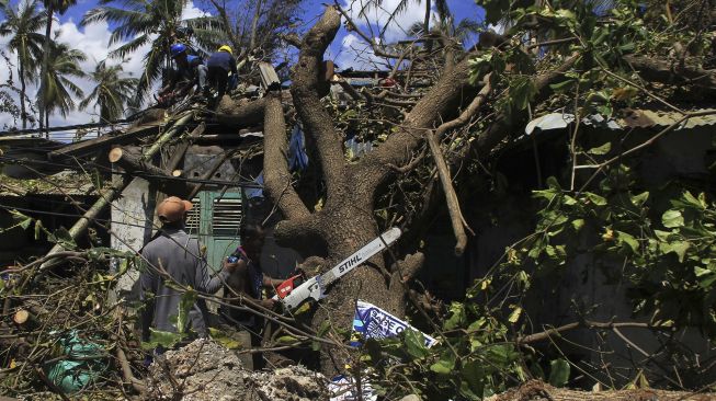 Sejumlah petugas memotong pohon yang tumbang menimpa salah satu rumah karena diterjang gelombang kencang akibat badai Siklon tropis Seroja di Kota Kupang, NTT, Kamis (8/4/2021). [ANTARA FOTO/Kornelis Kaha]