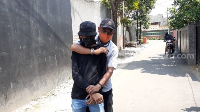 Ketua RT Mahligai Kencana saat memeragakan memiting pelaku perampok bersenjata usai menggagalkan aksi percobaan perampokan di Jalan Suka Bakti 1, Serua Indah, Ciputat, Kota Tangsel, ditemui di kediamannya, Jumat (9/4/2021). [Suara.com/Wivy Hikmatullah]