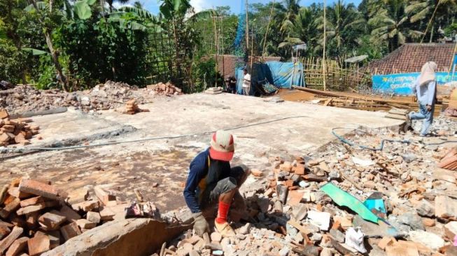 Warga membersihkan puing bangunan rumahnya yang hancur terdampak Gempa Malang, persisnya di Dusun Sidodadi Pulungdowo Desa Jogomulyan Tritoyudo, Minggu (11/4/2021). [Suara.com/Bob Bimantara L]