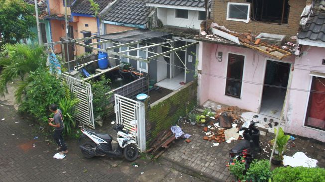 Seorang warga melintas di depan rumah yang rusak akibat gempa di Majangtengah, Malang, Jawa Timur, Minggu (11/4/2021).  ANTARA FOTO/Ari Bowo Sucipto

