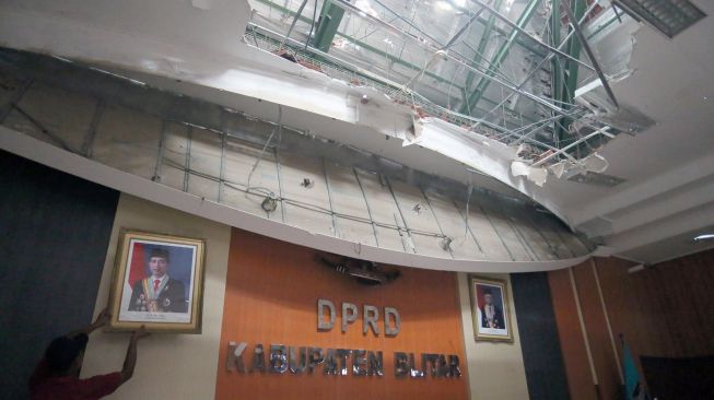 Petugas membersihkan puing-puing yang runtuh di Ruang Sidang Paripurna DPRD Kabupaten Blitar akibat gempa bumi di Blitar, Jawa Timur, Sabtu (10/4/2021).  ANTARA FOTO/Irfan Anshori
