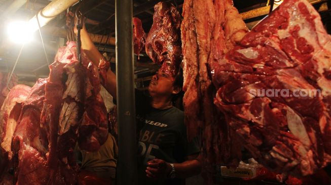 Pedagang menggantung daging di Pasar Bantargebang, Kota Bekasi, Minggu (11/4/2021). [Suara.com/Dian Latifah] 
