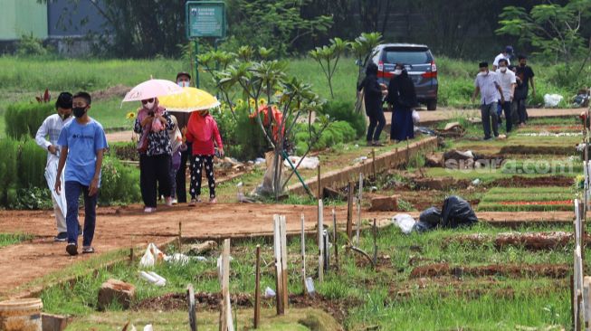 Warga saat datang untuk ziarah di area pemakaman khusus Covid - 19 TPU Bambu Apus, Jakarta Timur, Minggu (11/4/2021). [Suara.com/Alfian Winanto]