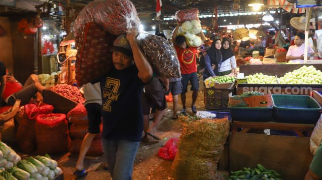 Aktivitas para pedagang di Pasar Induk Kramat Jati, Jakarta Timur, Minggu (11/4/2021). [Suara.com/Alfian Winanto]