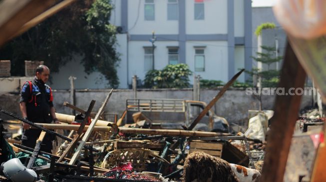 Petugas penjaga keamanan meninjau Pasar Kebon Melati setelah kebekaran di Jalan Sabeni Raya, Jakarta, Senin (12/4/2021). [Suara.com/Dian Latifah]