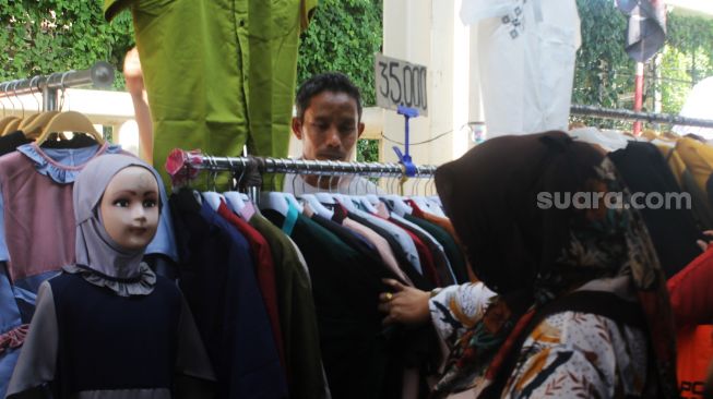 Pembeli memilih baju di Pasar Tanah Abang, Jakarta Pusat, Senin (12/4/2021). [Suara.com/Dian Latifah]