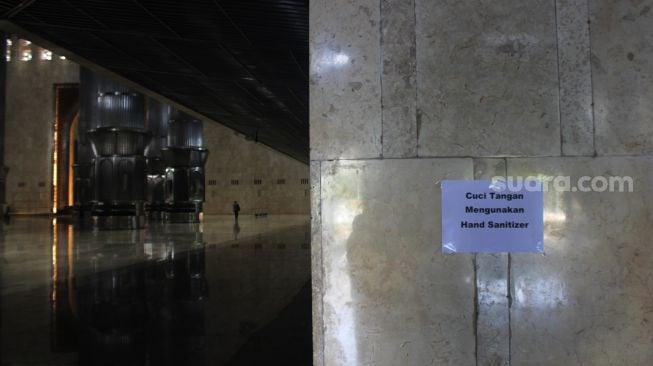 Himbauan mencuci tangan terpasang di setiap pintu masuk menuju Masjid Istiqlal Jakarta, Senin (12/4/2021). [Suara.com/Dian Latifah]