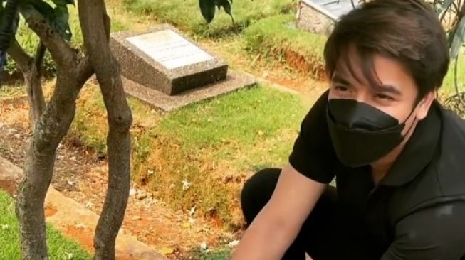 Billy Syahputra membersihkan makam almarhum sang kakak, Olga Syahputra. [Instagram]