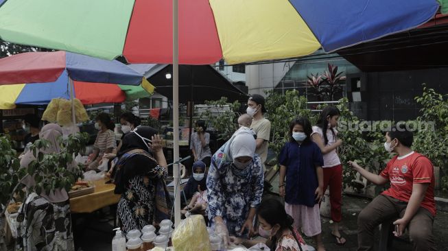 Pedagang melayani pembeli takjil dan makanan berbuka puasa di Pasar Takjil Benhil, Jakarta, Selasa (13/4/2021). [Suara.com/Angga Budhiyanto]