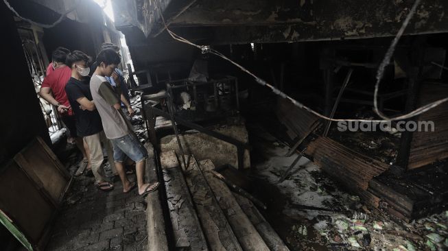 Warga menyaksikan sisa-sisa kebakaran di Pasar Minggu, Jakarta, Selasa (13/4/2021). [Suara.com/Angga Budhiyanto]