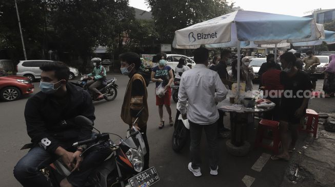 Pedagang melayani pembeli takjil dan makanan berbuka puasa di Pasar Takjil Benhil, Jakarta, Selasa (13/4/2021). [Suara.com/Angga Budhiyanto]