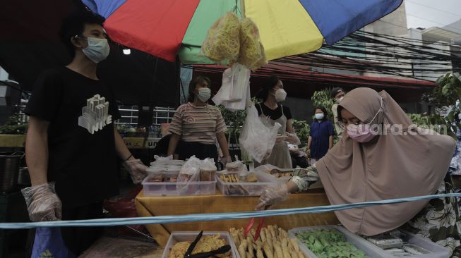 Pedagang menata takjil dan makanan berbuka puasa di Pasar Takjil Benhil, Jakarta, Selasa (13/4/2021). [Suara.com/Angga Budhiyanto]