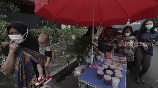 Pedagang melayani pembeli takjil dan makanan berbuka puasa di Pasar Takjil Benhil, Jakarta, Selasa (13/4/2021). [Suara.com/Angga Budhiyanto]