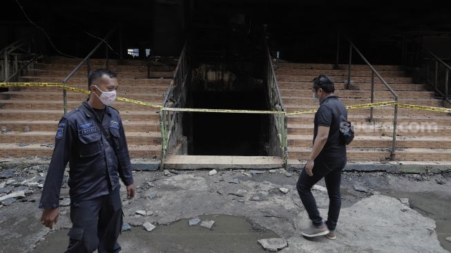 Petugas keamanan berjaga di dekat sisa-sisa kebakaran di Pasar Minggu, Jakarta, Selasa (13/4/2021). [Suara.com/Angga Budhiyanto]