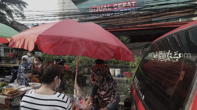 Pedagang melayani pembeli takjil dan makanan berbuka puasa di Pasar Takjil Benhil, Jakarta, Selasa (13/4/2021). [Suara.com/Angga Budhiyanto]