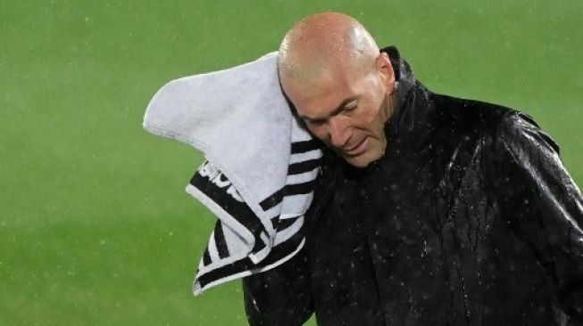Pelatih Real Madrid Zinedine Zidane menyeka kepalanya dengan handuk usai pertandingan La Liga kontra Barcelona di Estadio Alfredo Di Stefano, 11 April 2021. [AFP]