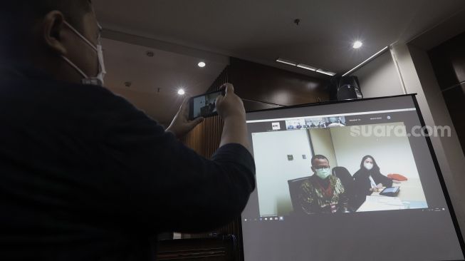 Jurnalis mengambil gambar Mantan Menteri Kelautan dan Perikanan Edhy Prabowo (kiri) saat sidang perdana dalam kasus suap ekspor benih lobster yang berlangsung secara virtual di Gedung Merah Putih KPK, Jakarta, Kamis (15/4/2021). [Suara.com/Angga Budhiyanto]