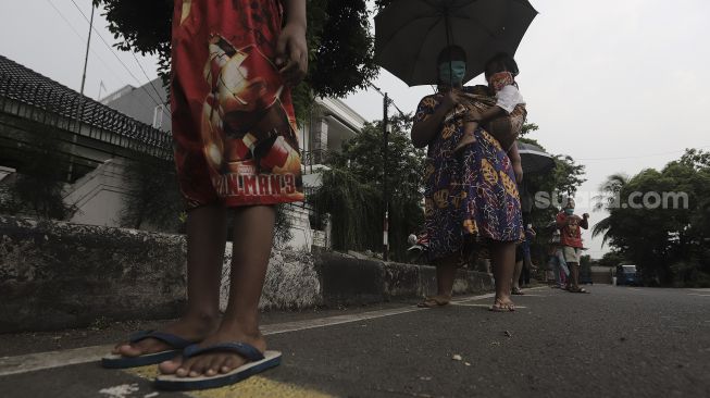 Sejumlah warga mengantre untuk mendapatkan takjil gratis di jalan Cempaka Putih Tengah XXI, Jakarta, Kamis (15/4/2021). [Suara.com/Angga Budhiyanto]