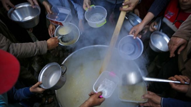 Warga mengantri mendapatkan sup gratis untuk berbuka puasa di tengah pandemi Covid-19 di Gaza, Palestina, Rabu (14/4).  MOHAMMED ABED / AFP
