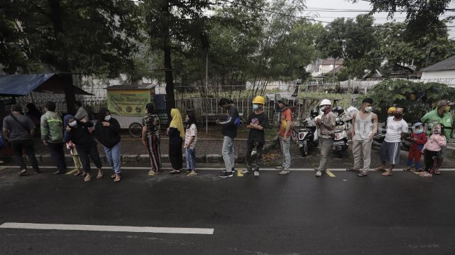 Sejumlah warga mengantre untuk mendapatkan takjil gratis di jalan Cempaka Putih Tengah XXI, Jakarta, Kamis (15/4/2021). [Suara.com/Angga Budhiyanto]