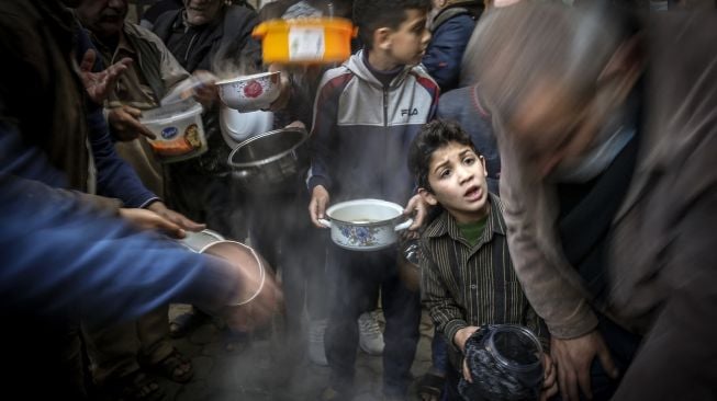 Warga mengantri mendapatkan sup gratis untuk berbuka puasa di tengah pandemi Covid-19 di Gaza, Palestina, Rabu (14/4).  MOHAMMED ABED / AFP
