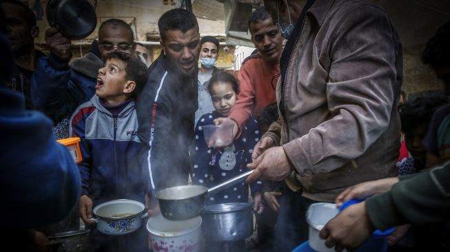 Warga mengantri mendapatkan sup gratis untuk berbuka puasa di tengah pandemi Covid-19 di Gaza, Palestina, Rabu (14/4).  MOHAMMED ABED / AFP
